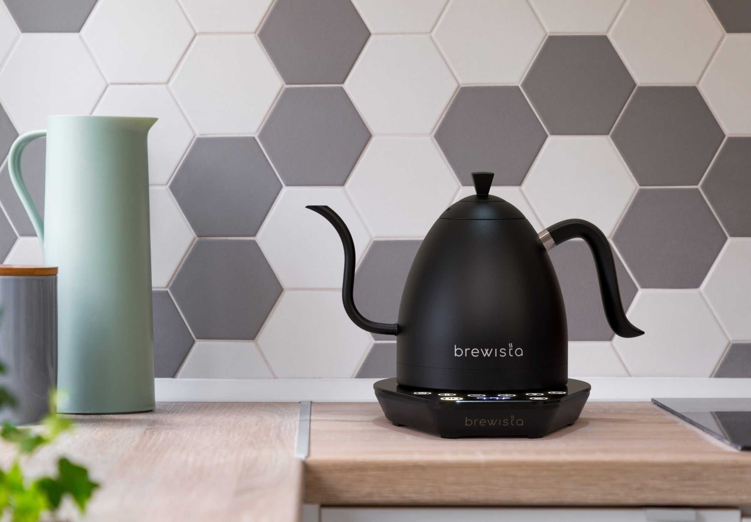 Black Brewista Artisan kettle sitting on a counter in a modern kitchen. The backsplash has hexagonal tiles.